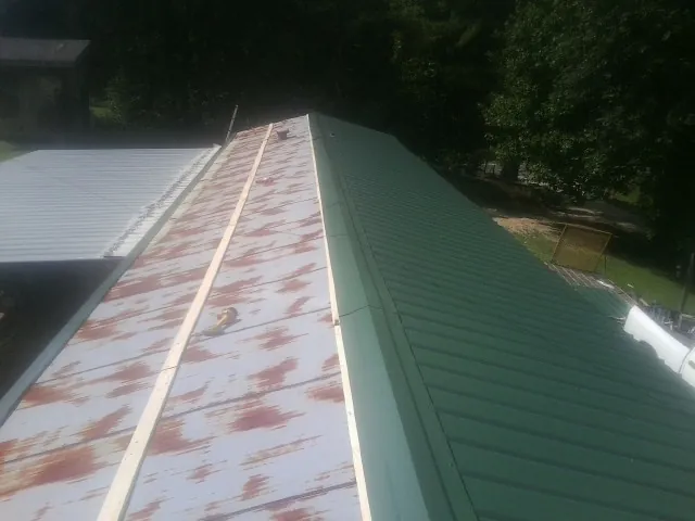 Old rusted panels beside newly installed green metal roofing — Wind Damage Roof Repair by Roofing Brothers in Pemberville
