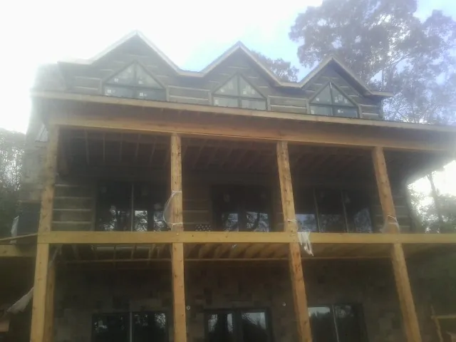 Dormers and porch framing on a large log home under construction — Roof Coating work by our crew in Pemberville