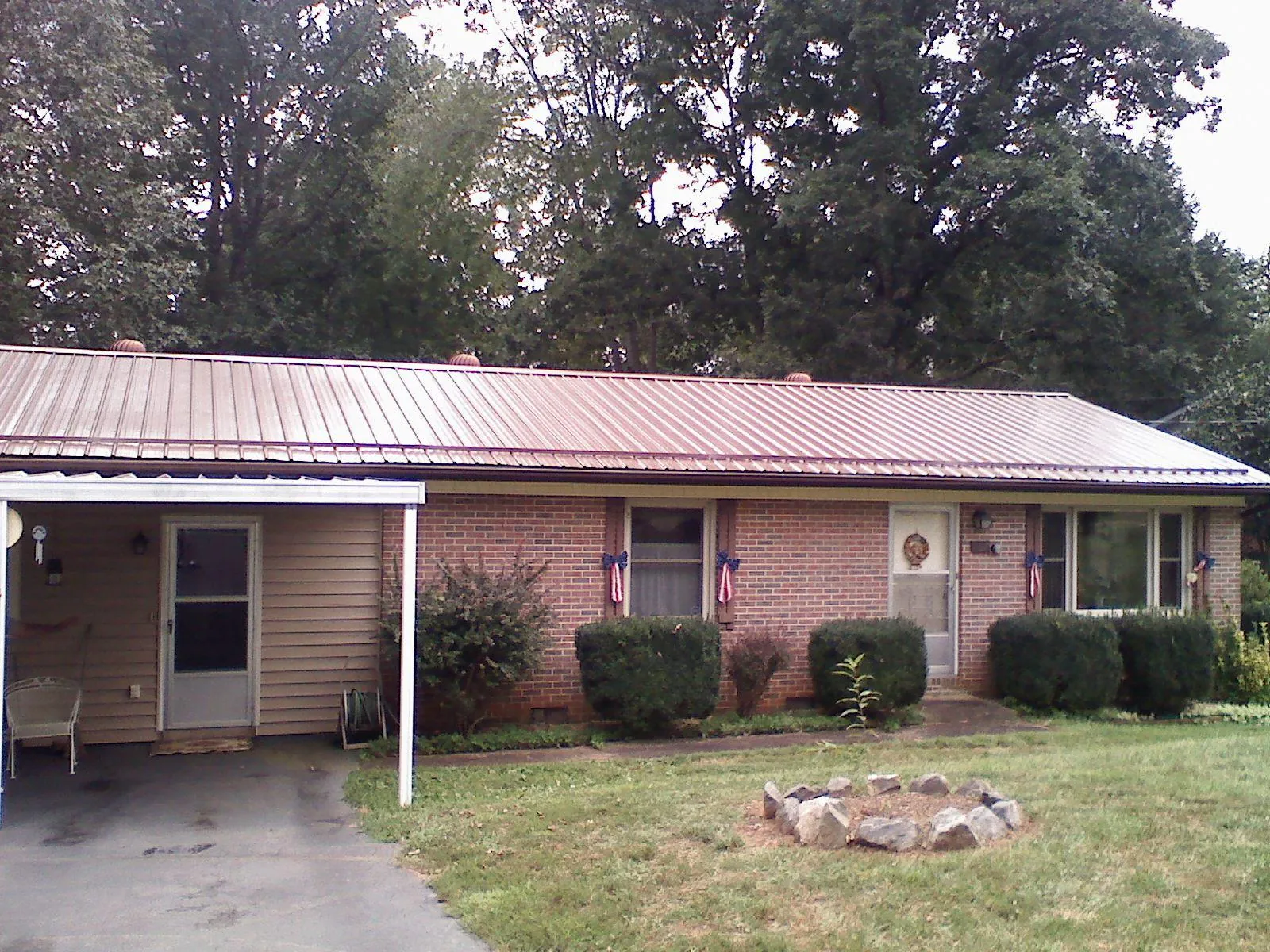 Bronze metal roof and carport on a brick ranch home — Roof Repair work by our crew in Pemberville