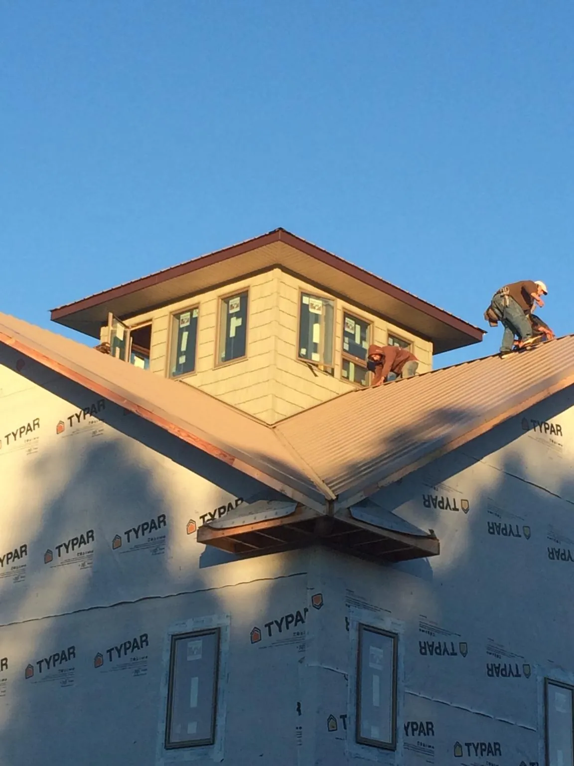 Roofers working around a rooftop cupola on a new metal roof at sunset — Roof Waterproofing in Pemberville by Roofing Brothers